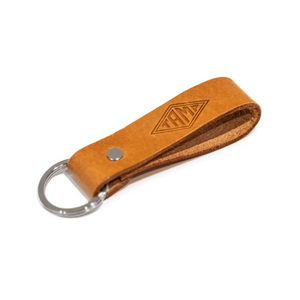 close-up view of a handcrafted natural brown leather keyring from Tamp Coffee, featuring intricate stitching and embossed logo detail