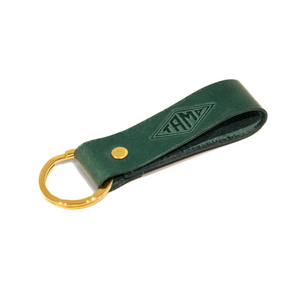 close-up view of a handcrafted green leather keyring from Tamp Coffee, featuring intricate stitching and embossed logo detail