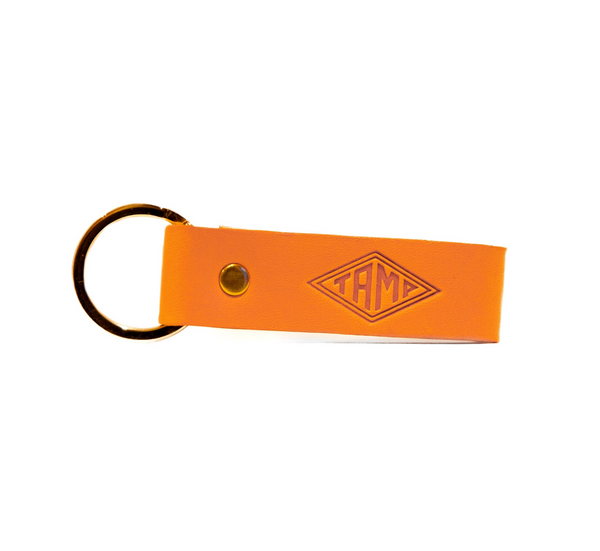 front view of a handcrafted orange leather keyring from Tamp Coffee, featuring intricate stitching and embossed logo detail